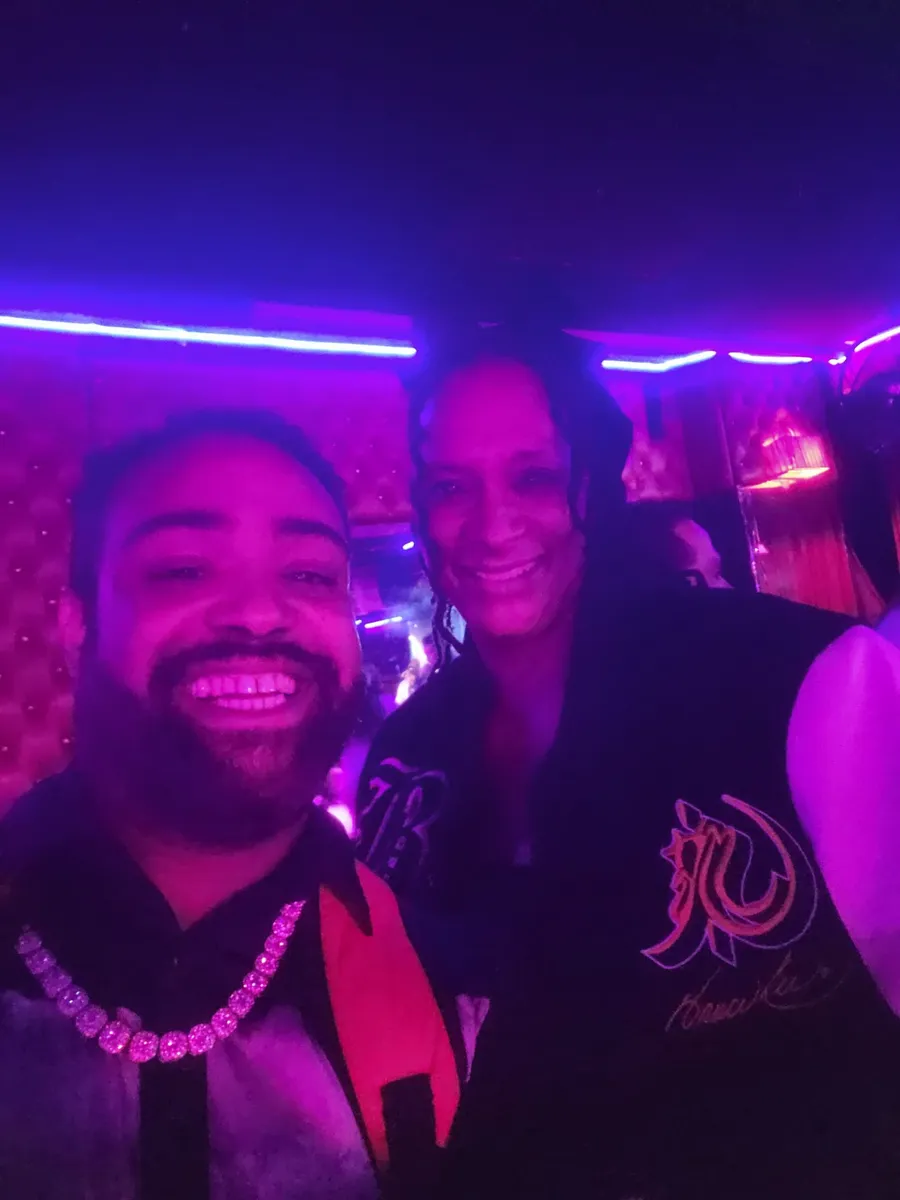 JC smiling in a selfie with another guest under purple neon at a BET weekend event