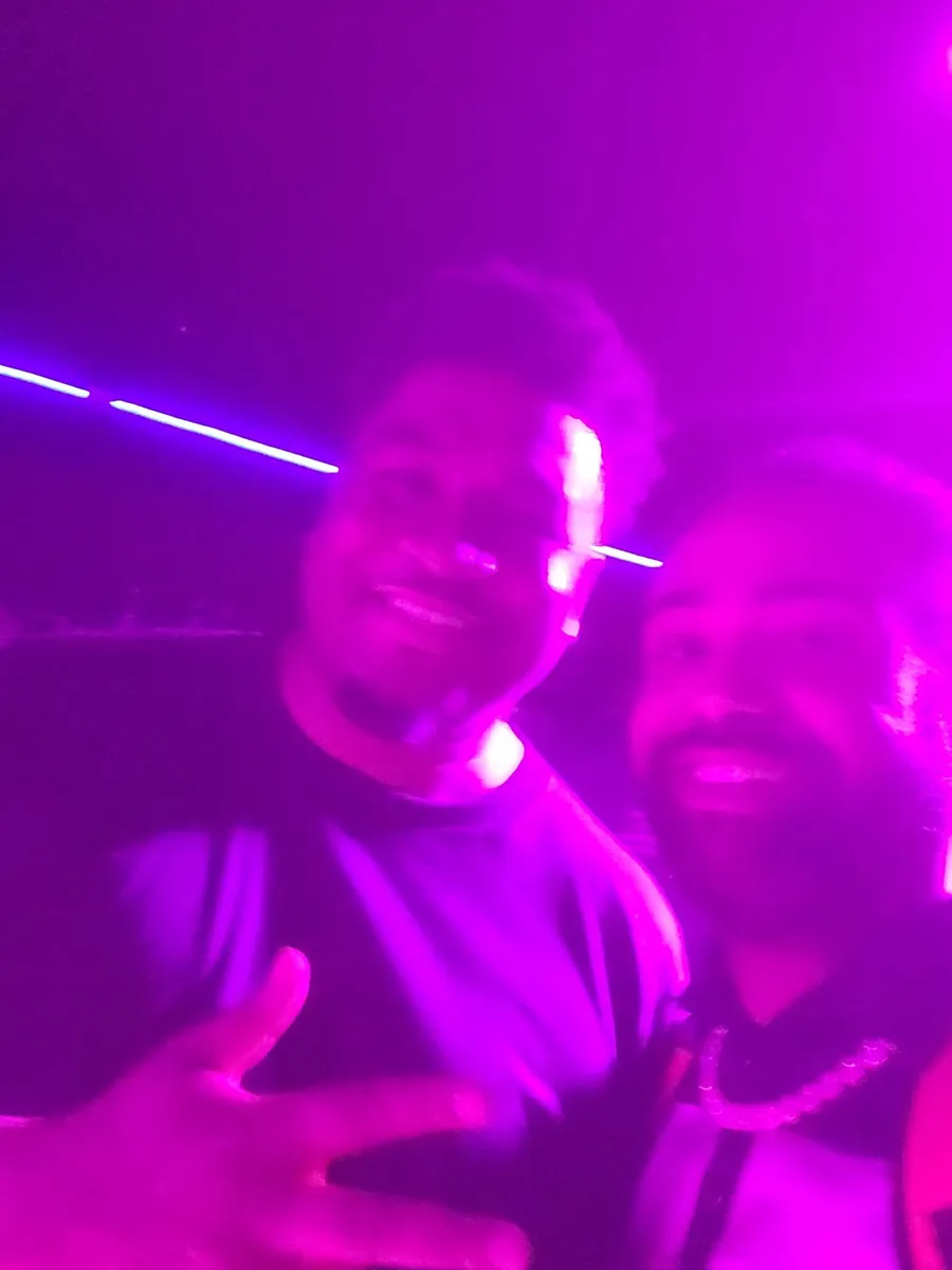 JC and another guest in a purple-lit selfie, flashing a peace sign at a BET weekend event