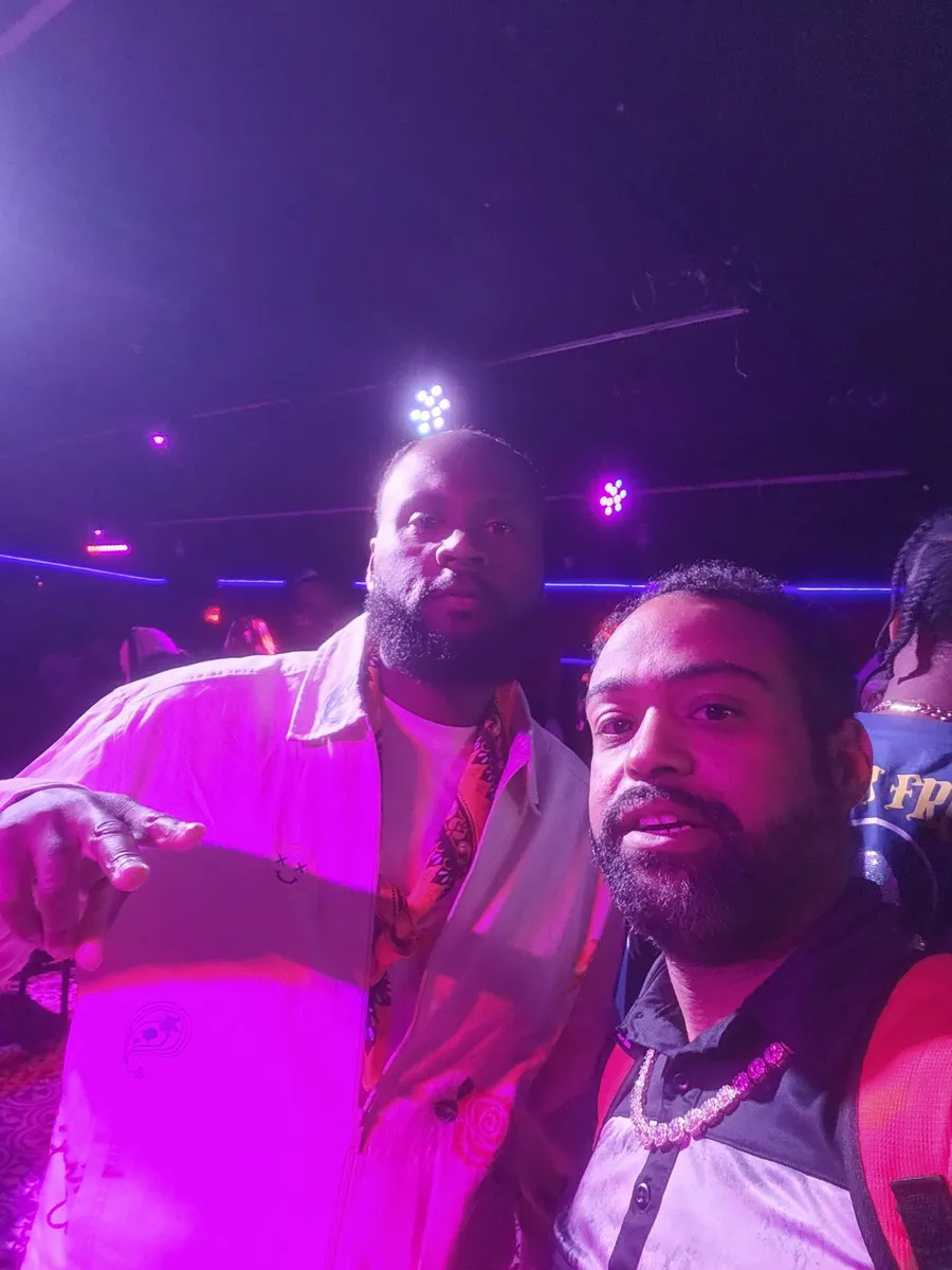 JC in a selfie with another guest under the purple stage lights at a BET weekend event